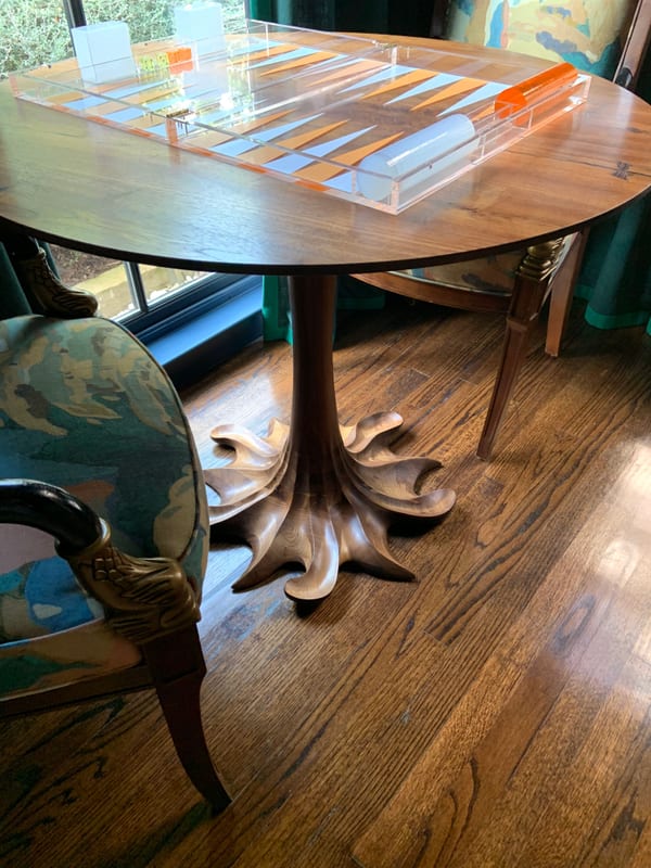 A close view of a carved pedestal table set with glass and a globe on wood floors.
