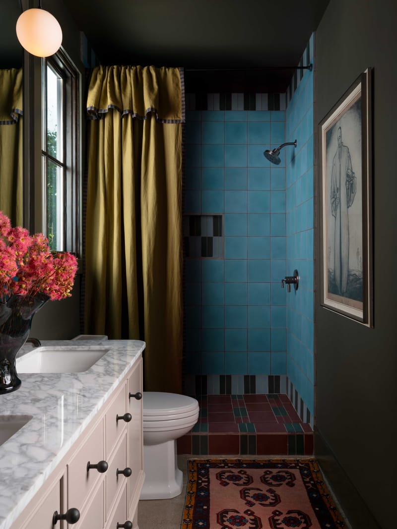 A bathroom with a gold silk curtain beside a turquoise tiled shower.