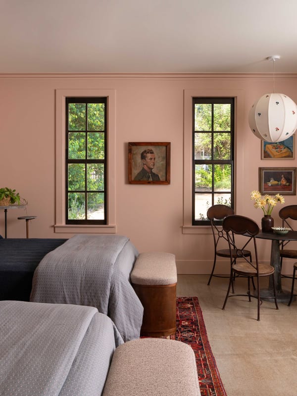 A pink-walled living room looking toward tall black-framed windows.